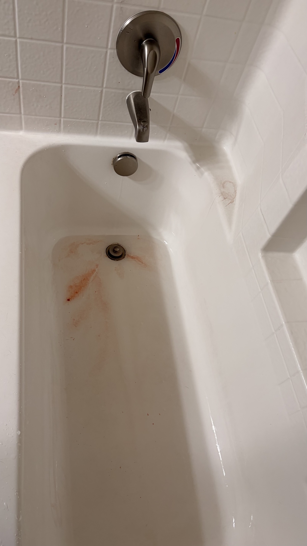 Dirty bathtub with heavy pink staining around the drain before cleaning