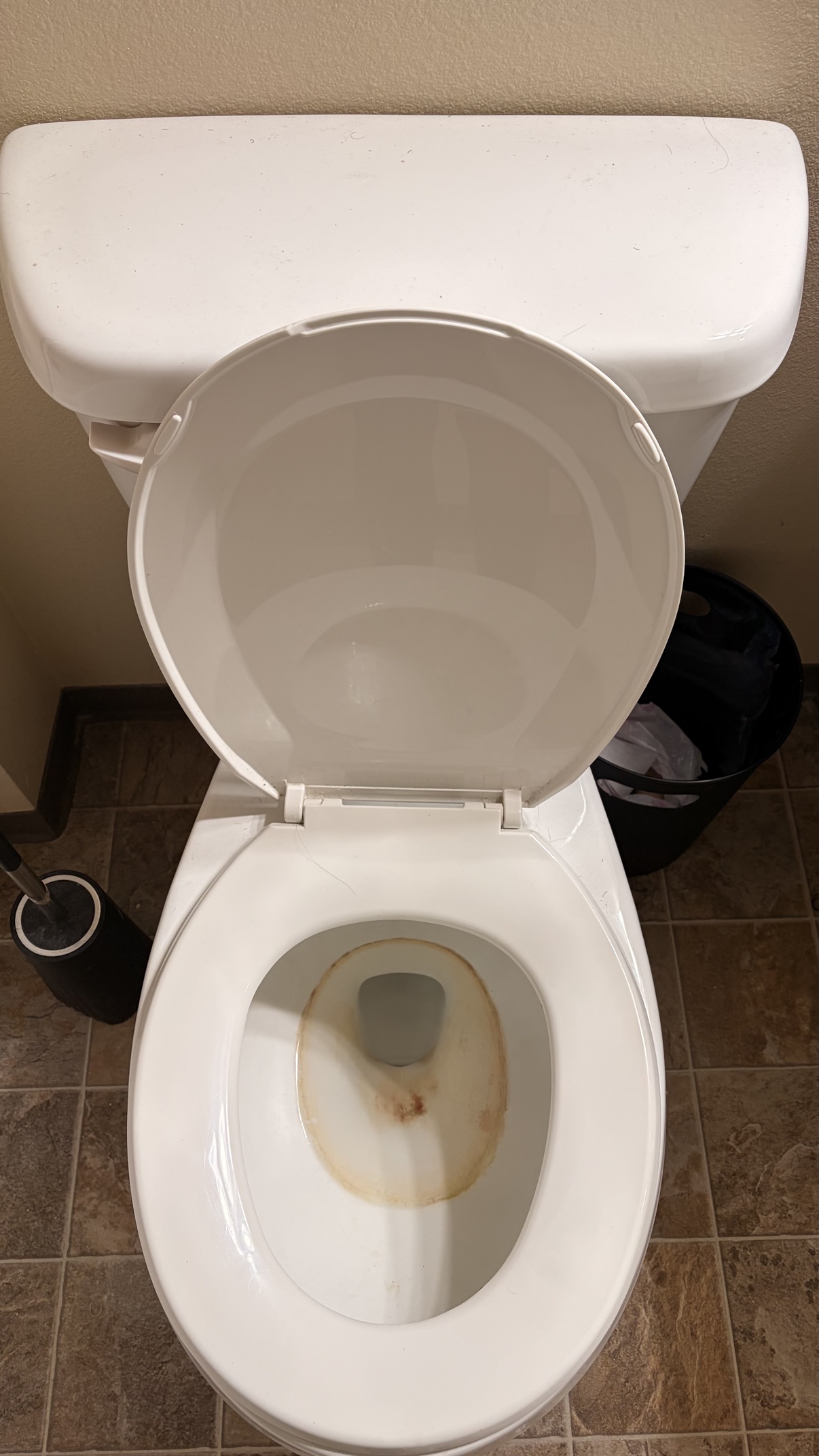 Toilet bowl with a brown and yellow stain ring before cleaning